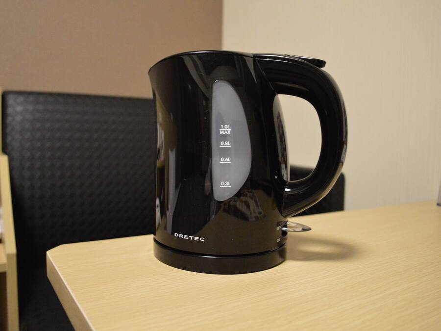 A black electric kettle on a wooden table with measurement markings.
