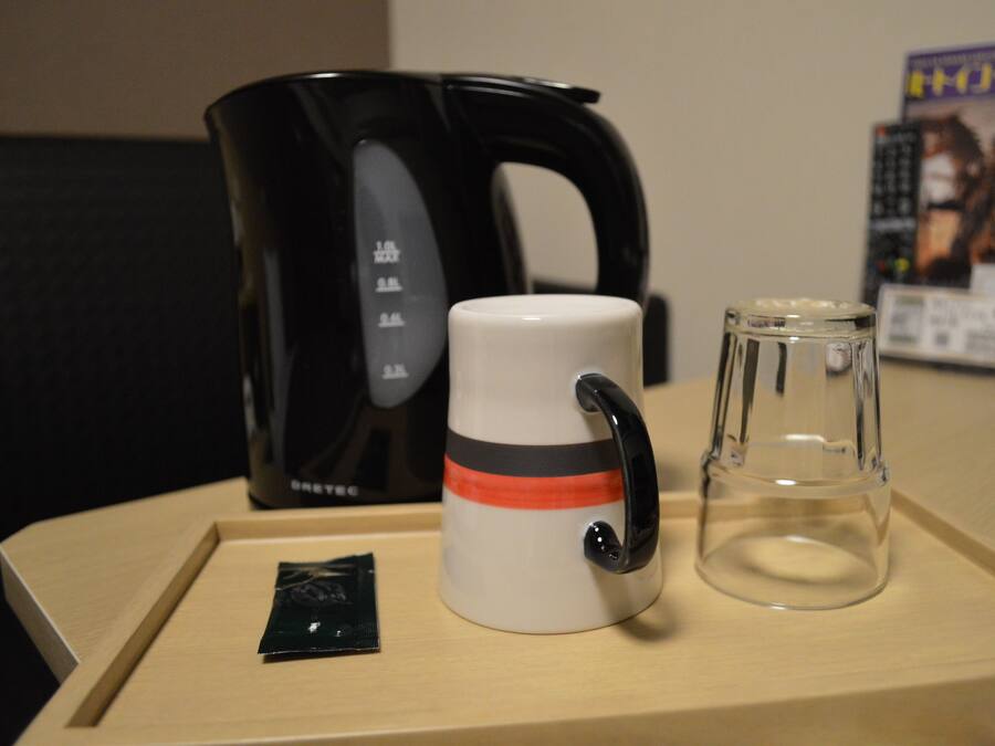 A coffee maker, a mug, and a glass on a tray.