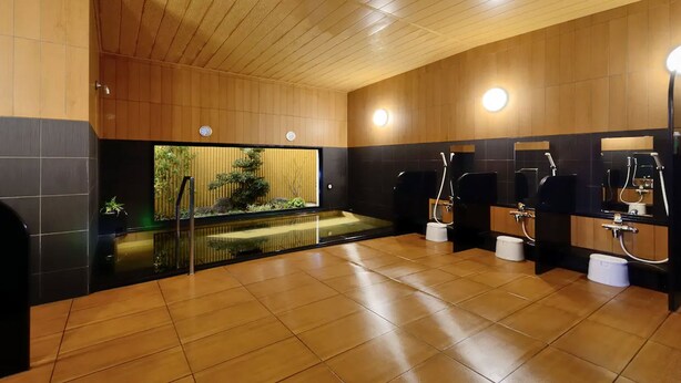 Un baño moderno con paneles de madera, separador de vidrio y varios lavamanos con secamanos.