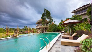 A swimming pool with lounge chairs and a statue. - Om Ham Retreat and Resort (Ubud)