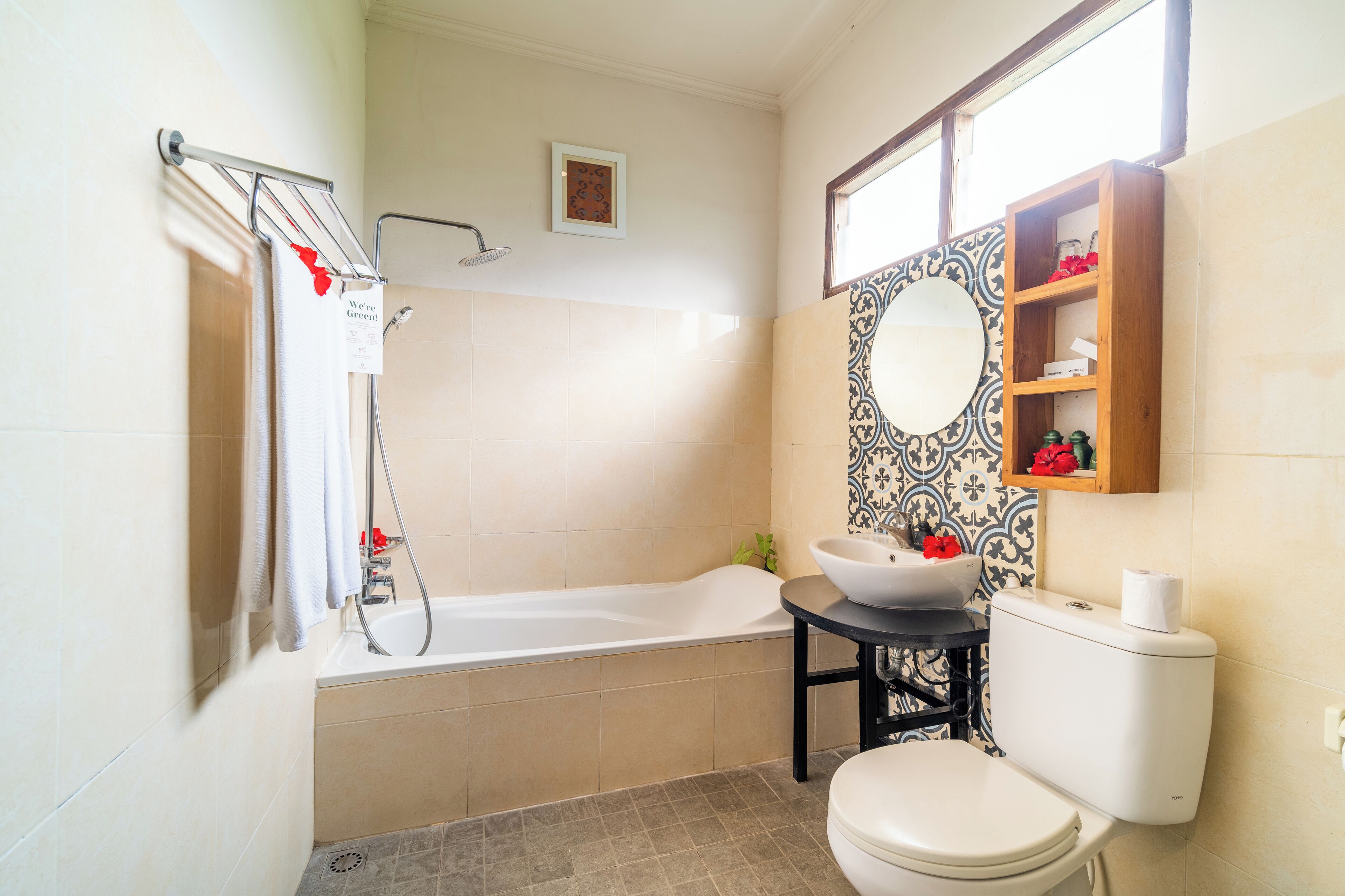 A bathroom with a bathtub, toilet, sink, and a mirror with a decorative tile backsplash.