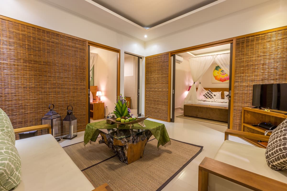 A modern hotel room with a dining area, a bed with a canopy, and a television.