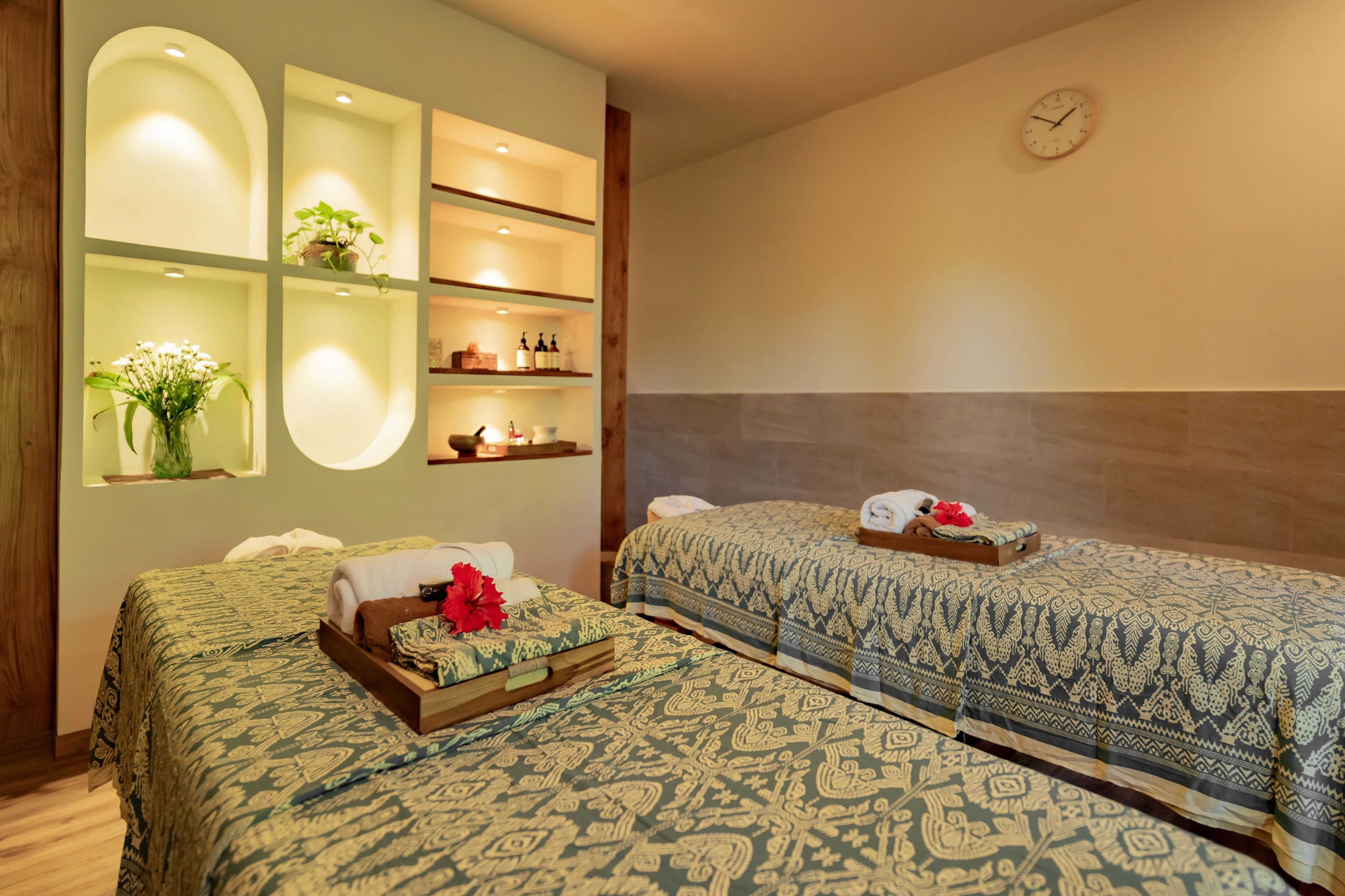 Ein Hotelzimmer mit zwei Betten, einer Wanduhr und Ablageflächen mit Toilettenartikeln.