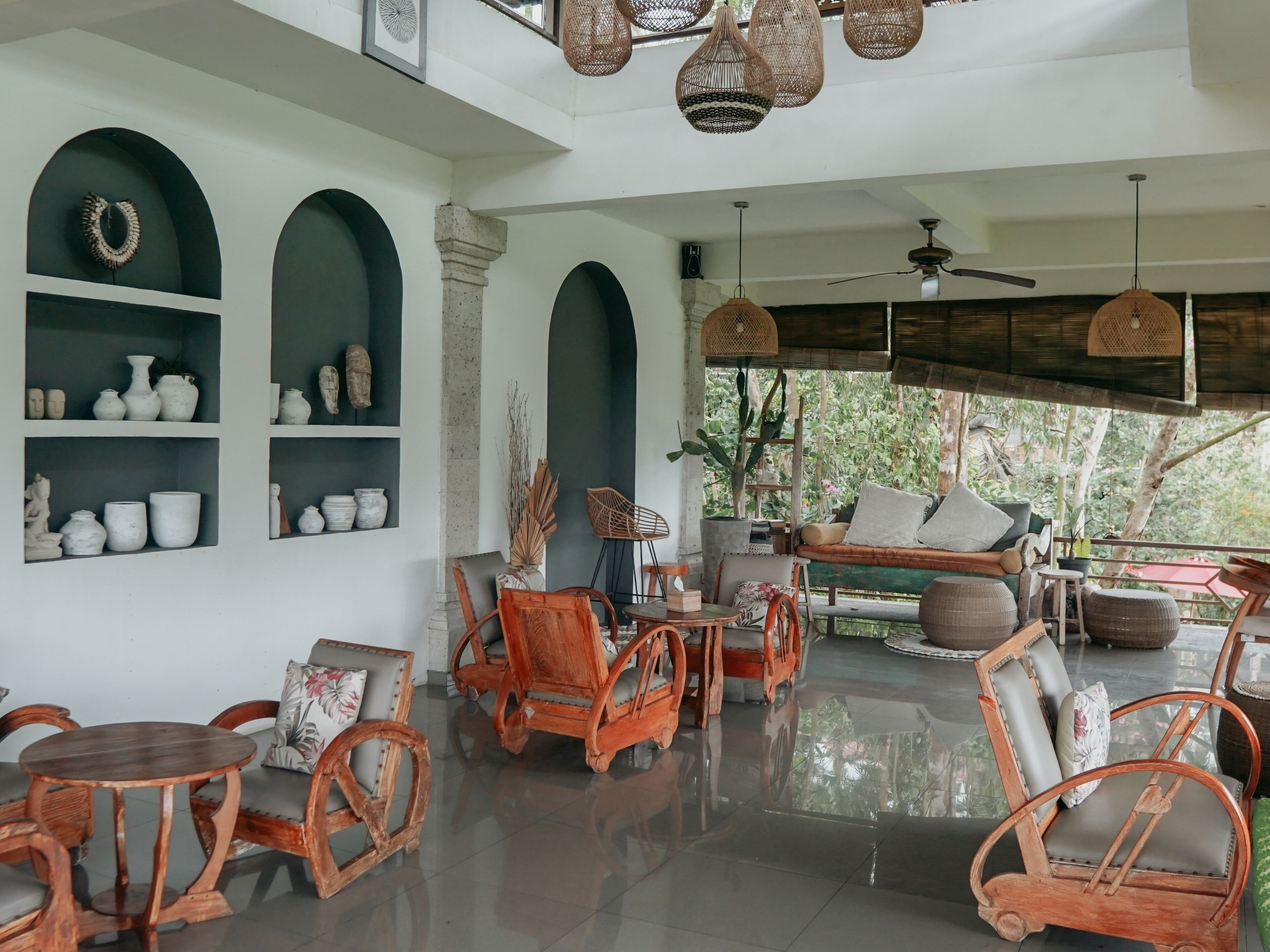 A spacious room with a high ceiling, wicker furniture, and a variety of decorative items on shelves.