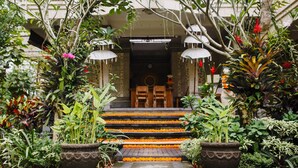A traditional entrance with steps adorned with orange flowers, surrounded by lush greenery and potted plants. - Om Ham Retreat and Resort (Ubud)