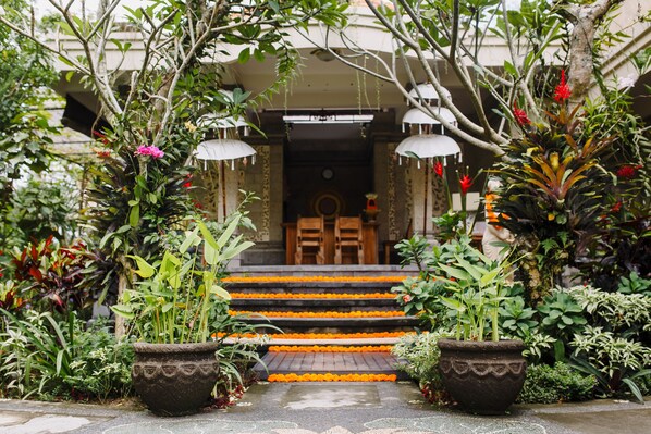 A traditional entrance with steps adorned with orange flowers, surrounded by lush greenery and potted plants. - Om Ham Retreat and Resort (Ubud)