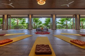 A spacious room with large windows, yoga mats, and a central bench. - Om Ham Retreat and Resort (Ubud)