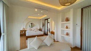 A modern hotel room with a large bed, a sofa, and a dining area. - Om Ham Retreat and Resort (Ubud)