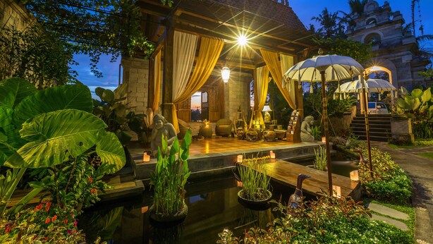 A serene garden with a pond, potted plants, and a gazebo with draped curtains. - Om Ham Retreat and Resort (Ubud)