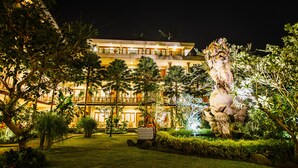 A large, illuminated building with a well-maintained garden and a statue. - Om Ham Retreat and Resort (Ubud)