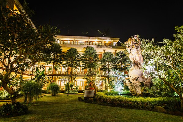 A large, illuminated building with a well-maintained garden and a statue. - Om Ham Retreat and Resort (Ubud)