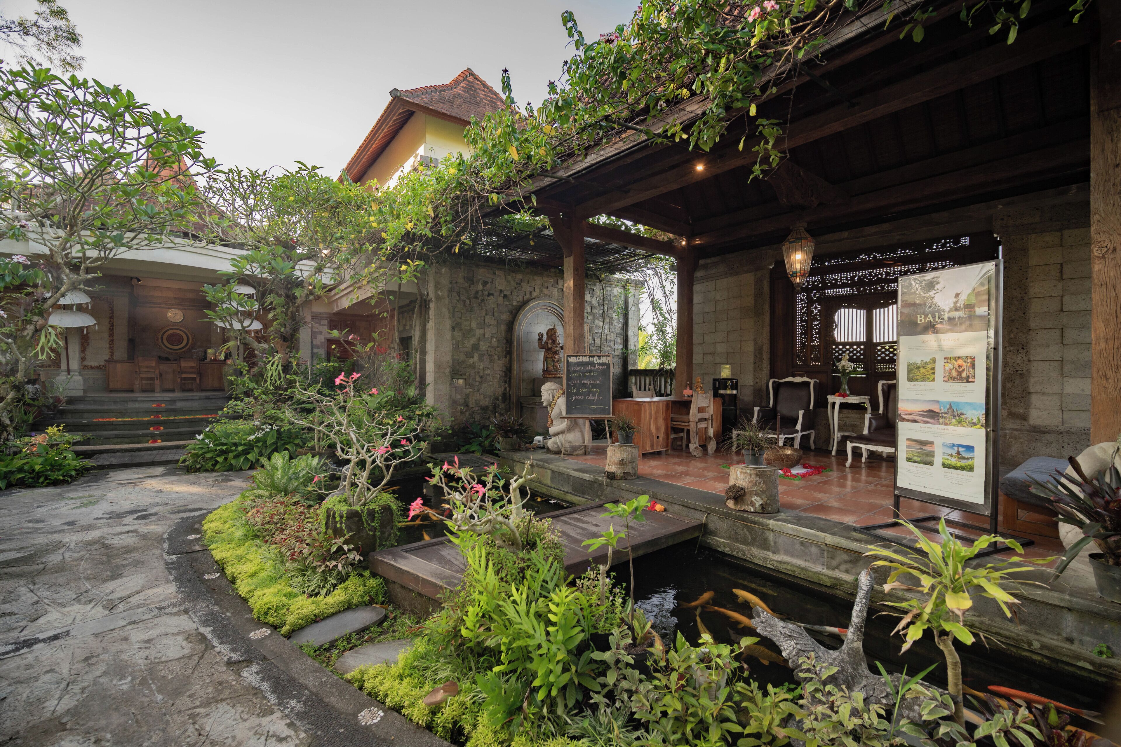 A courtyard with a koi pond, stone steps, and a wooden pergola.