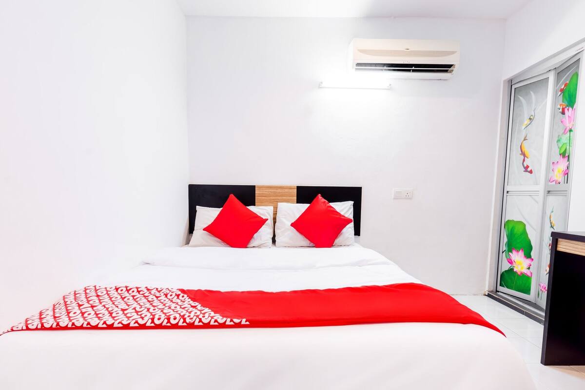 Una cama con ropa de cama blanca y roja, cabecero negro y una manta roja.