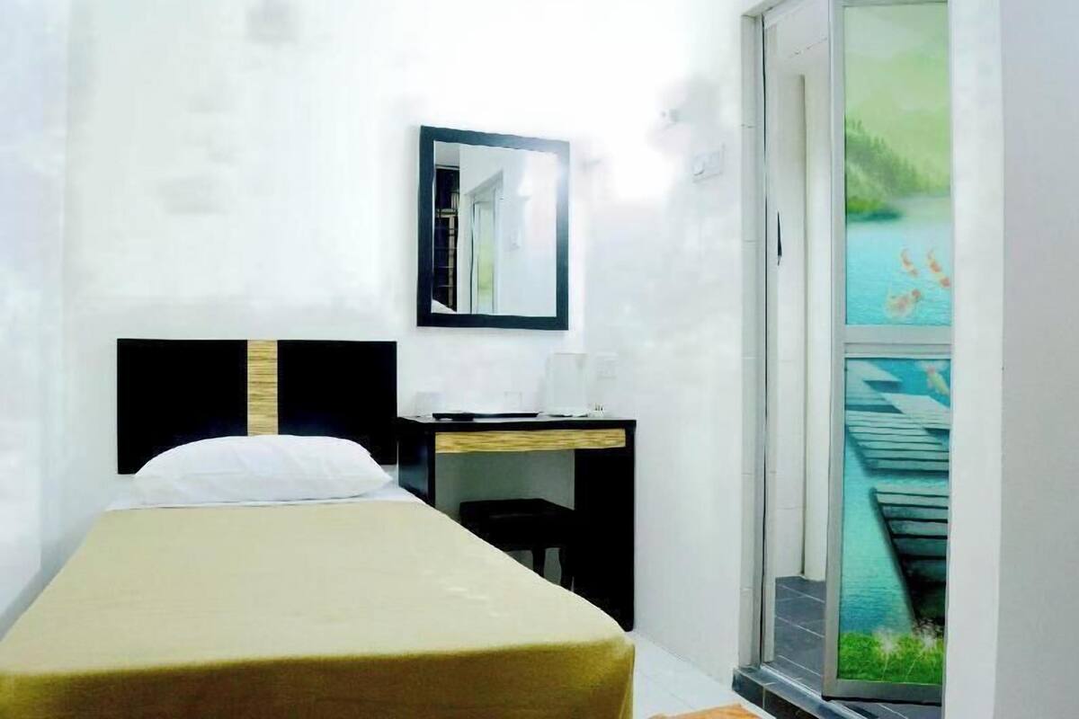 Habitación de hotel con cama, escritorio, silla, espejo y ventana con vista a un cuerpo de agua.