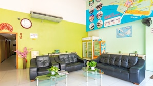 A reception area with a green wall, a map, a clock, and a seating area with leather sofas and glass tables. - Hotel Bao Shu (Malacca City)