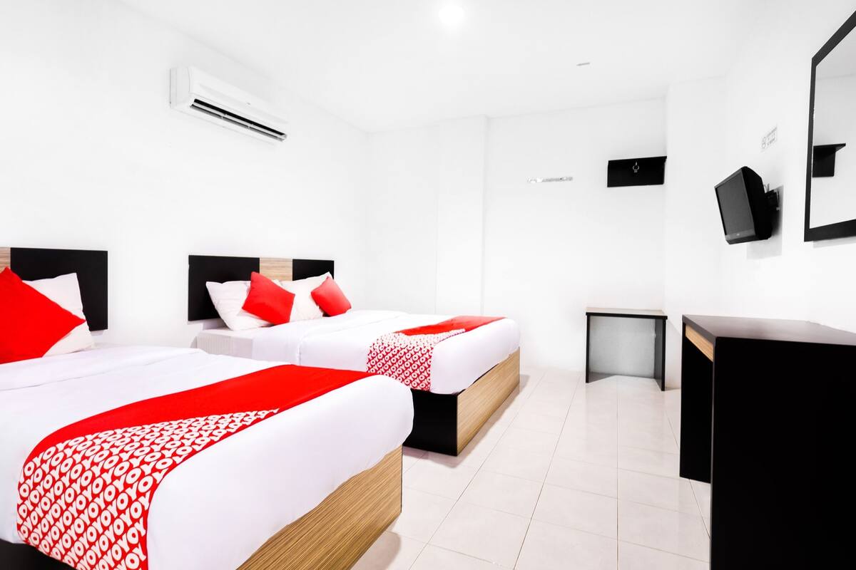 Habitación de hotel con dos camas, un escritorio y un televisor.