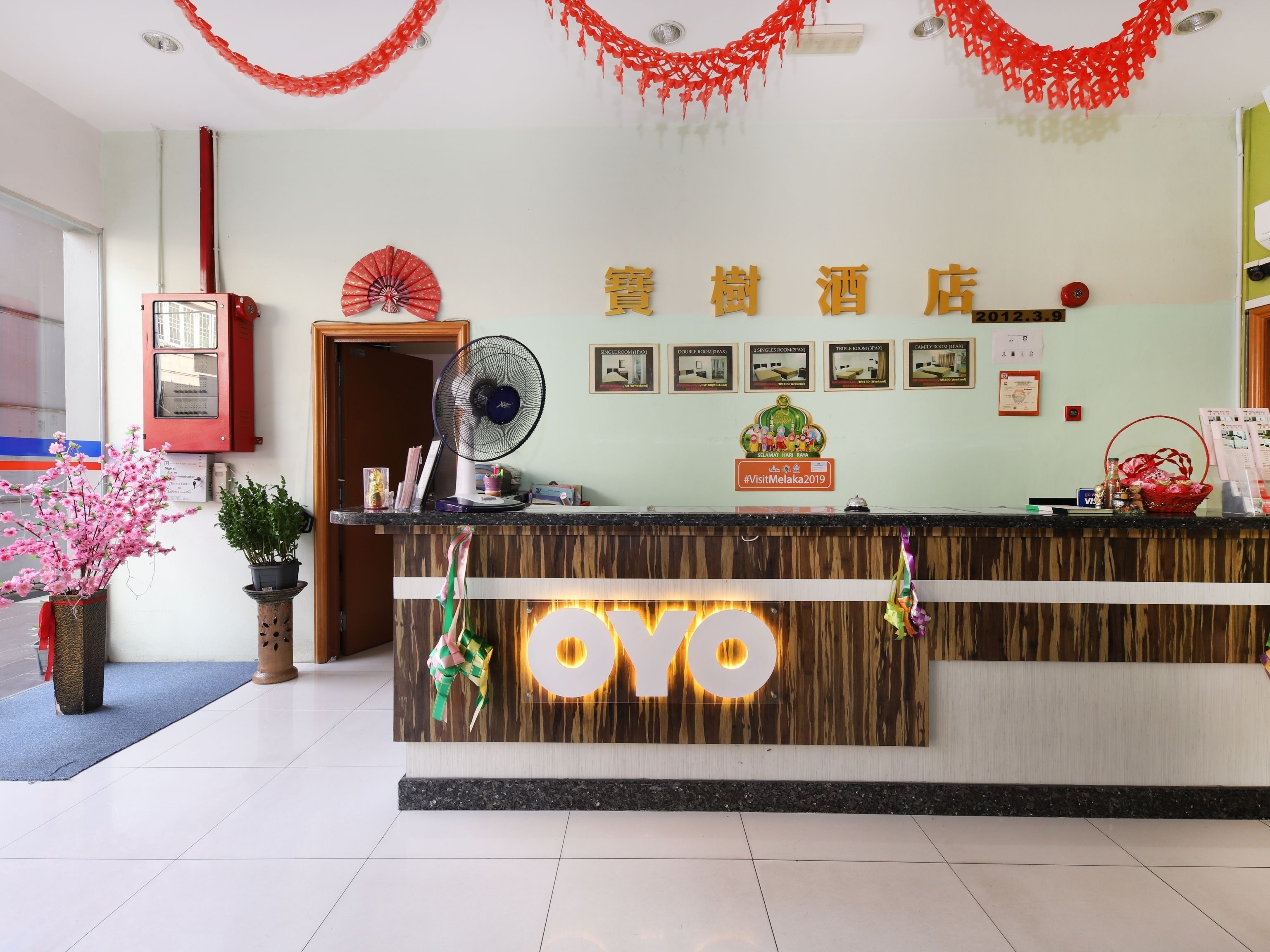 Una mesa de recepción de hotel con mostrador de madera, un ventilador y un letrero que dice "OYO".