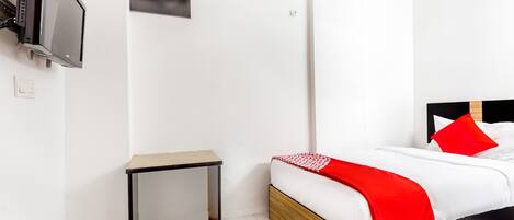 Una habitación de hotel con una cama, una mesita, un aire acondicionado y un televisor.