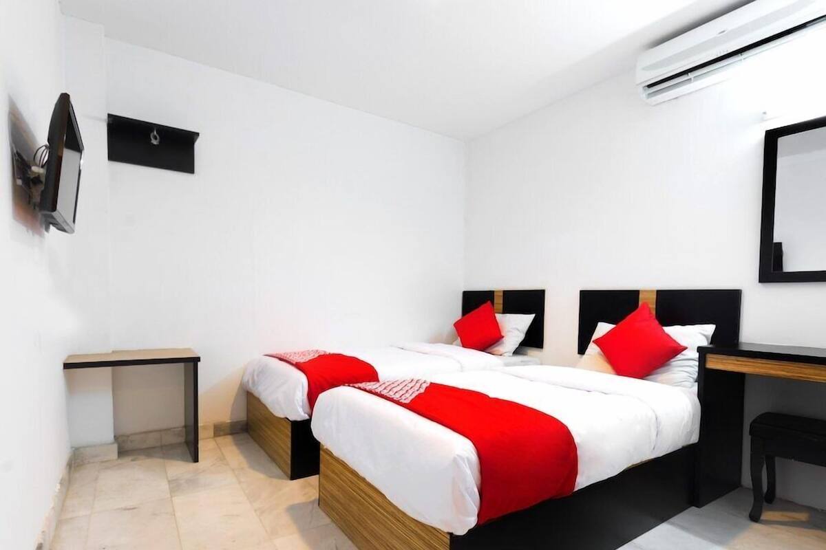Una habitación de hotel moderna con dos camas, un escritorio, una silla, una mesita y un equipo de aire acondicionado.