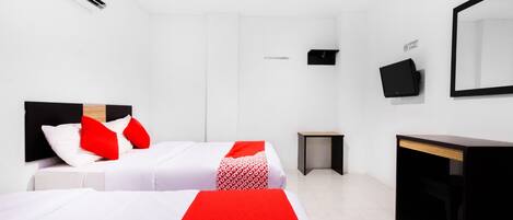 A hotel room with two beds, a desk, a chair, a small table, and a mirror.