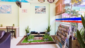 A cozy room with a map, a small garden area, a desk, and a bookshelf with magazines. - Hotel Bao Shu (Malacca City)