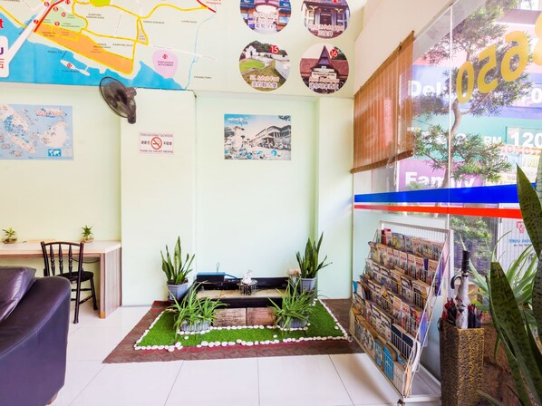 A cozy room with a map, a small garden area, a desk, and a bookshelf with magazines. - Hotel Bao Shu (Malacca City)