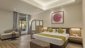 A modern hotel room with a large bed, a sofa, a small table, and a bench. - Sterling Nainital (Nainital)