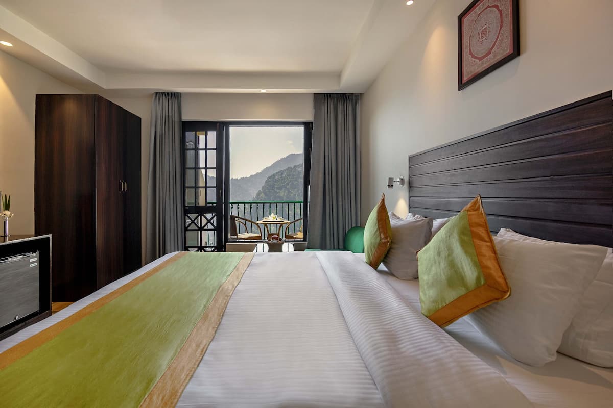 A hotel room with a large bed, a desk, and a view of mountains through the window.