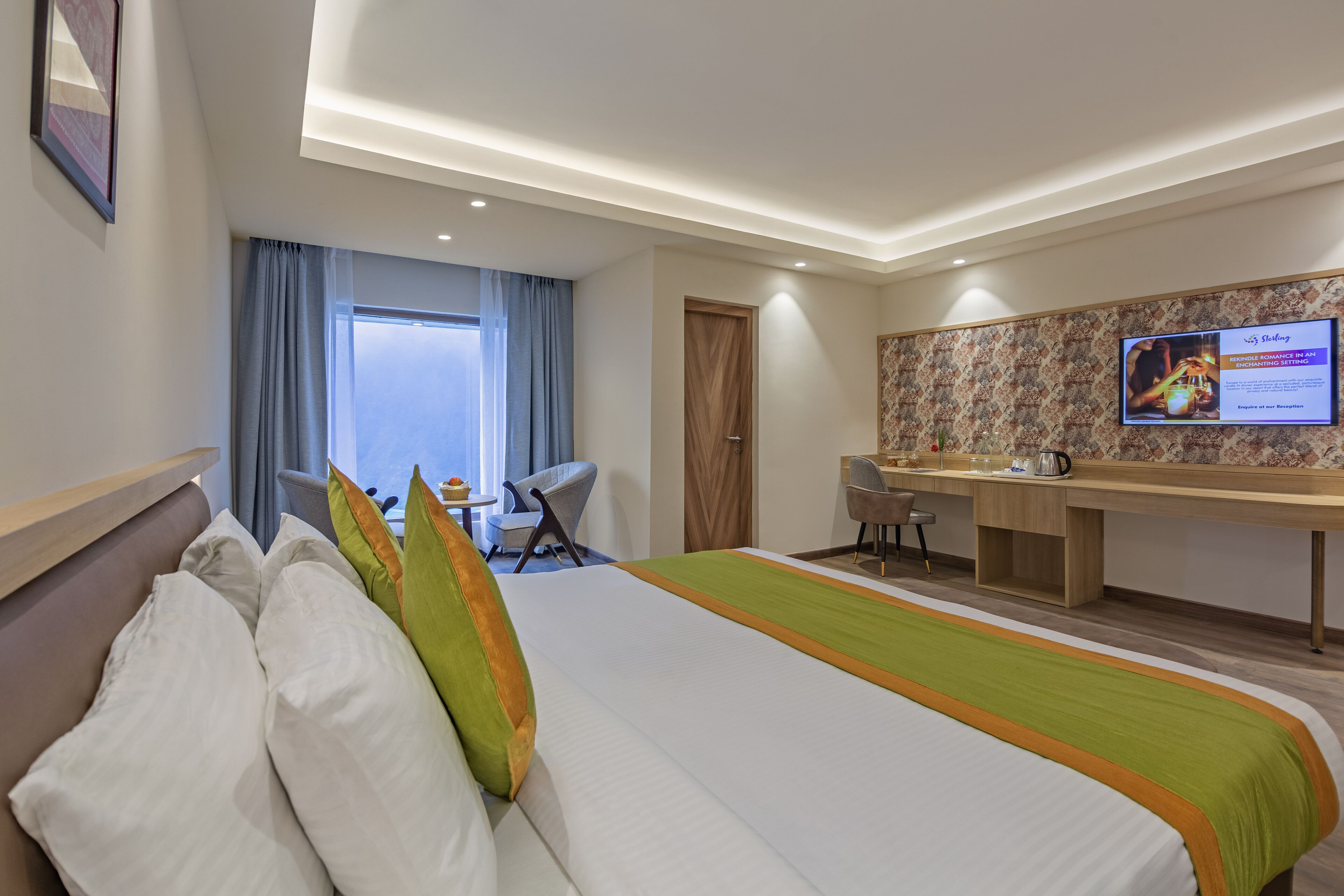 Una camera d'albergo con un letto, una scrivania, una sedia, una televisione e una finestra con tende.