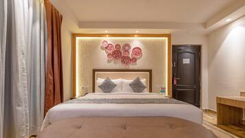 Habitación de hotel con una cama grande, cabecera de madera, panel decorativo en la pared, mesita de noche con una botella y una puerta con un letrero.