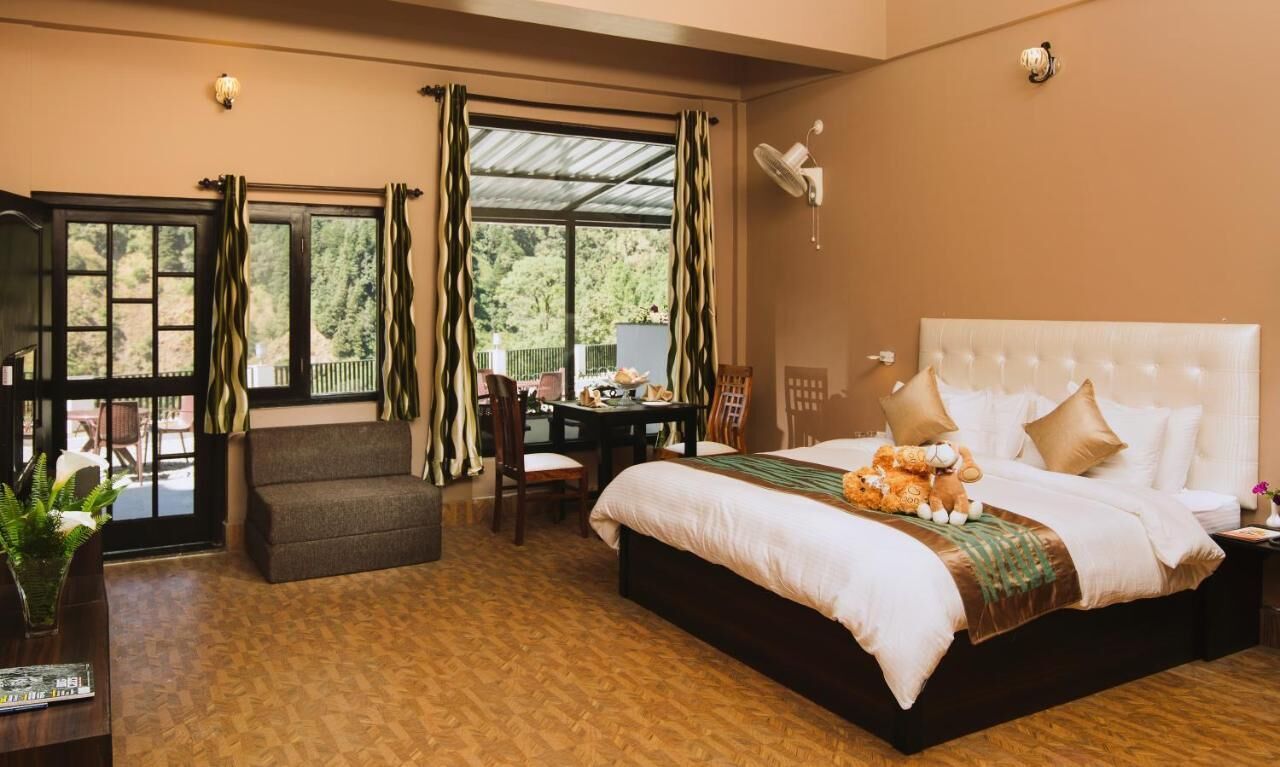 A bedroom with a large bed, a desk, a chair, and a view of the outdoors.