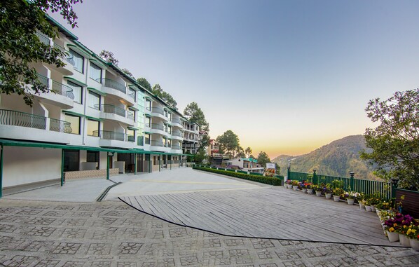 A hotel with multiple balconies, a covered outdoor area, and a scenic mountain view. - Sterling Nainital (Nainital)