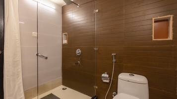 A modern bathroom with a glass shower enclosure, a toilet, and a small mirror.