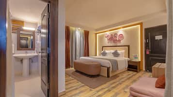 A hotel room with a bed, bedside table, and a bathroom with a sink and mirror.