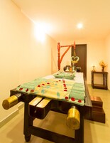 A massage table with a wooden frame, a green towel, and a heart-shaped decoration.