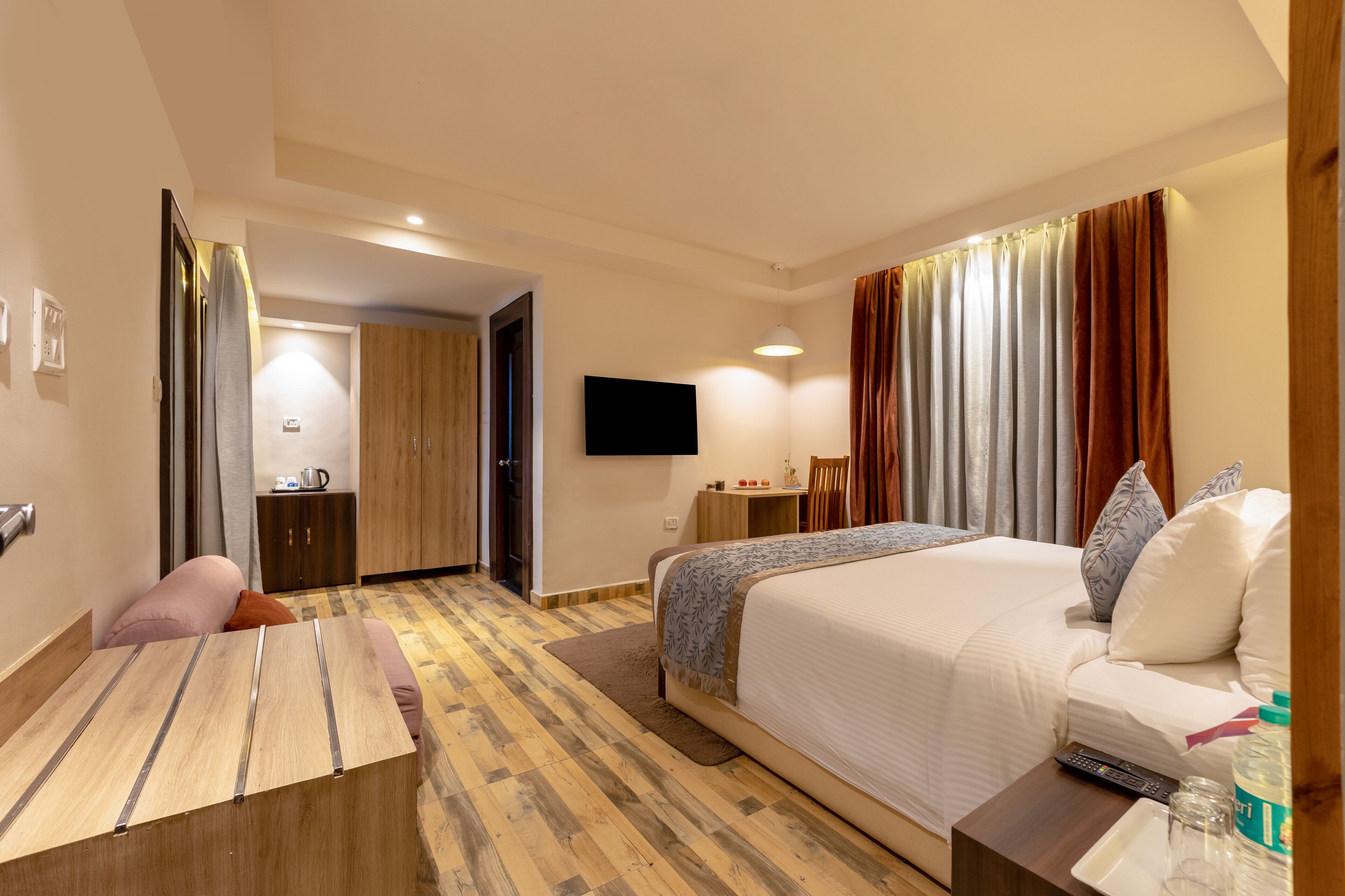 A hotel room with a bed, a desk, a television, and a bathroom visible through an open door.