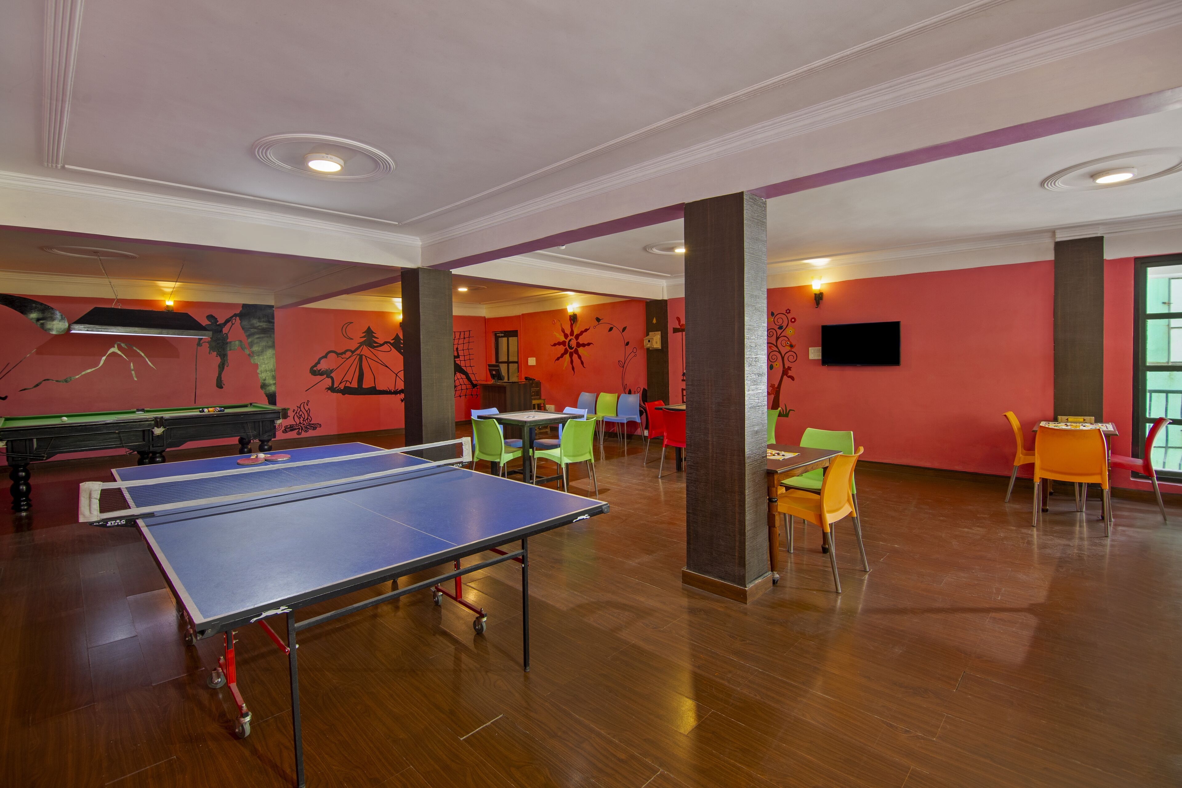 Una habitación con mesa de ping pong, sillas coloridas y mesa de billar.
