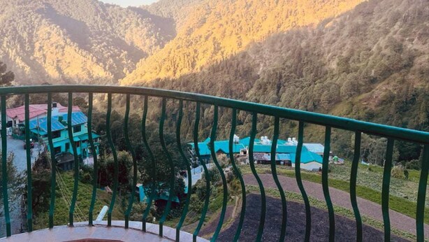 A mountainous landscape with a view of a building with a green roof and a balcony railing. - Sterling Nainital (Nainital)
