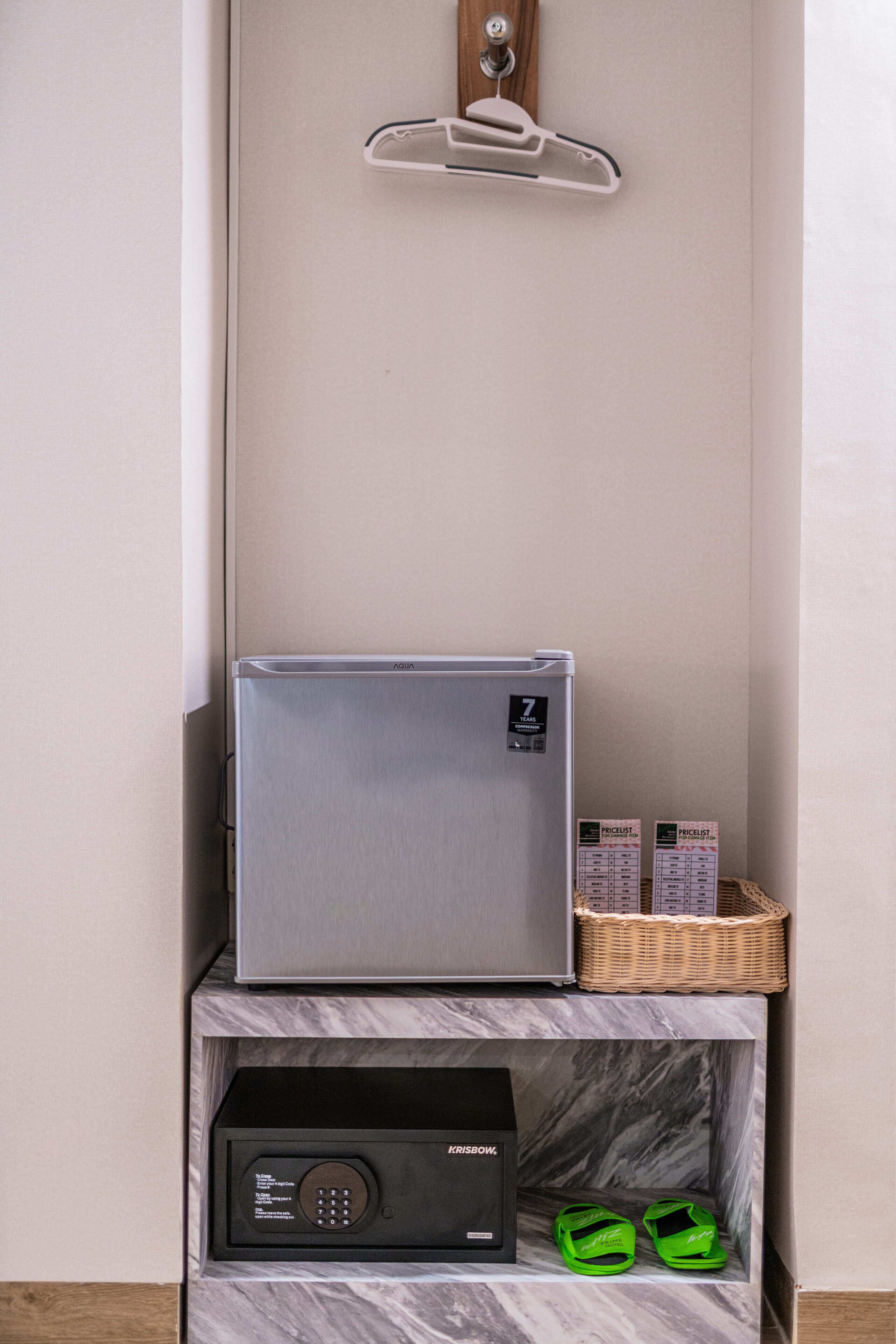 Un refrigerador compacto, una lista de precios y un pequeño dispositivo electrónico sobre un estante de mármol.