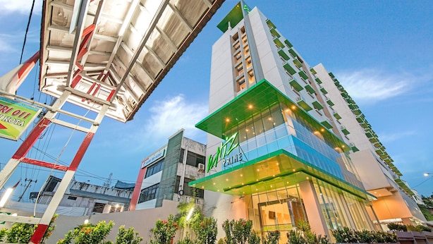 Un hotel moderno con un llamativo letrero que dice 'Prime', ventanas amplias y detalles verdes en la fachada.