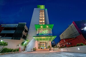 Un hotel llamado "WIZ PRIME" con un diseño moderno, destacando una entrada prominente y señalización iluminada.