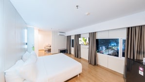 Una habitación de hotel moderna con una cama grande, un televisor y una ventana con cortinas.