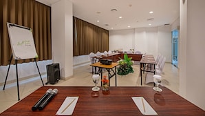 Un salón de conferencias con una gran mesa, una pizarra y equipo de audio.