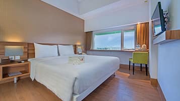 Relax in comfort with a large bed against a wall, a flat-screen TV, and a desk for work.