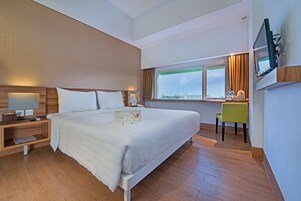 Una habitación de hotel con una cama grande, una mesita de noche, una lámpara y un televisor montado en la pared.
