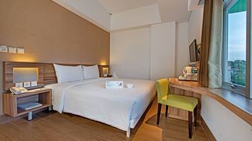 Habitación de hotel con una cama grande, mesitas de noche, un escritorio con silla, una ventana con cortinas y vistas al exterior.
