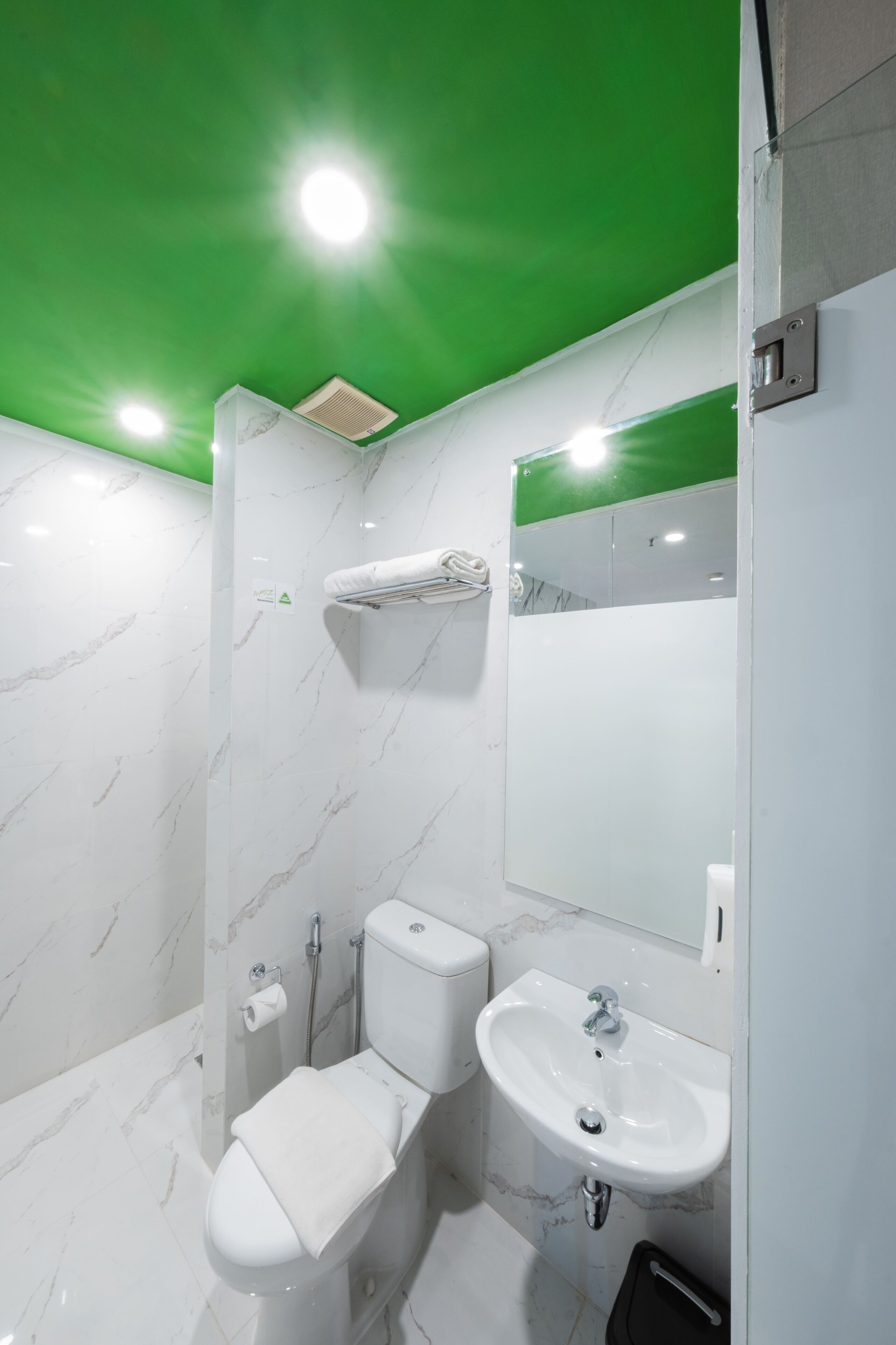 Un baño moderno con inodoro blanco, lavamanos y espejo.