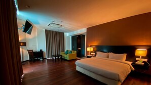 Habitación de hotel con una cama grande, lámparas de noche, un escritorio con silla y un televisor montado en la pared.