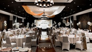 Un salón de banquetes con mesas redondas, sillas y un escenario con un letrero que dice 'Happy Birthday'.