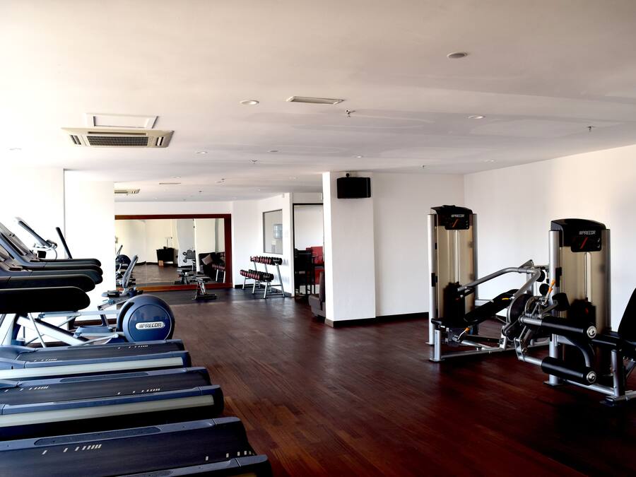 A gym with treadmills, weight machines, and a mirror.